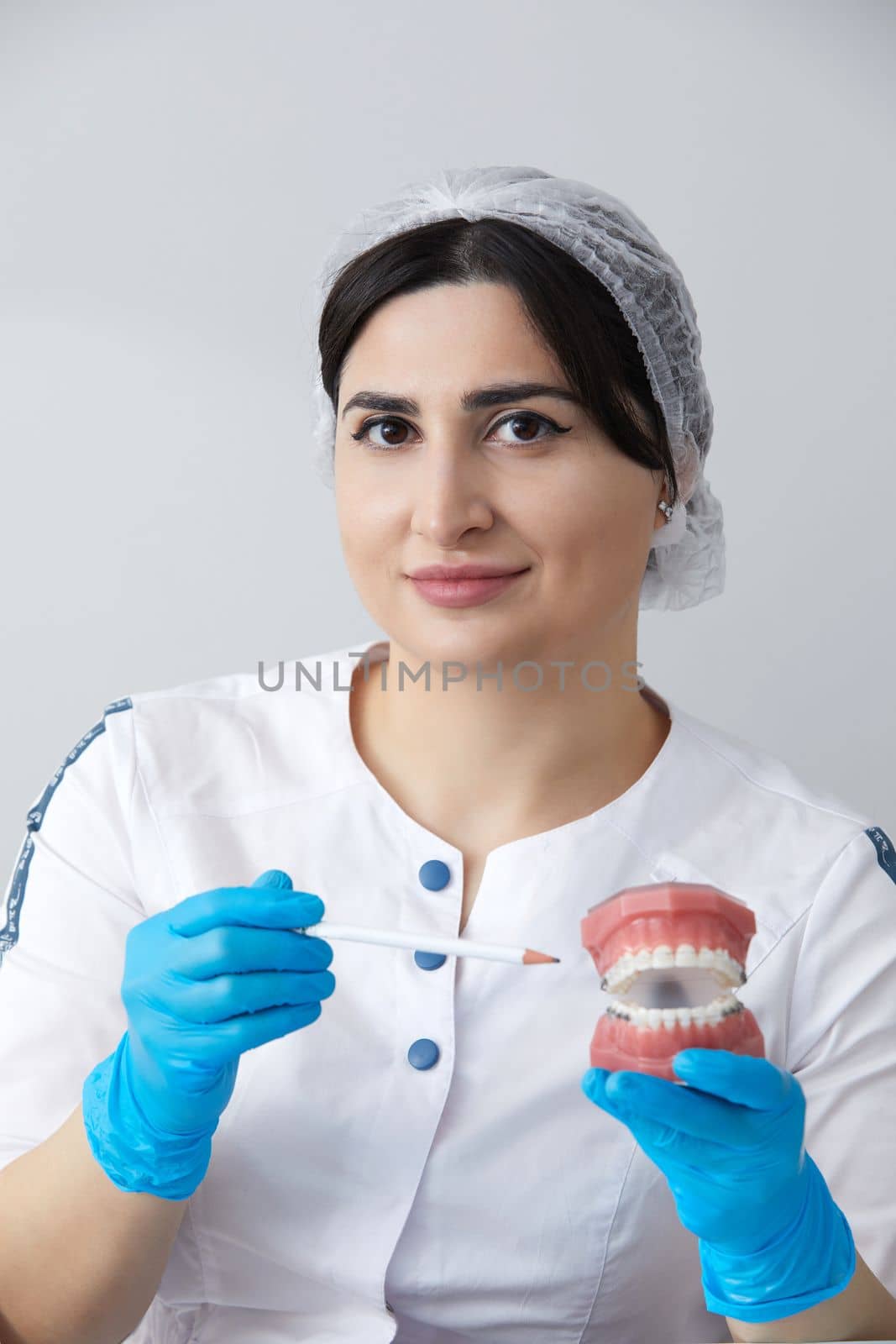 Doctor orthodontist showing model of human jaw with wire braces and aligners explaining difference