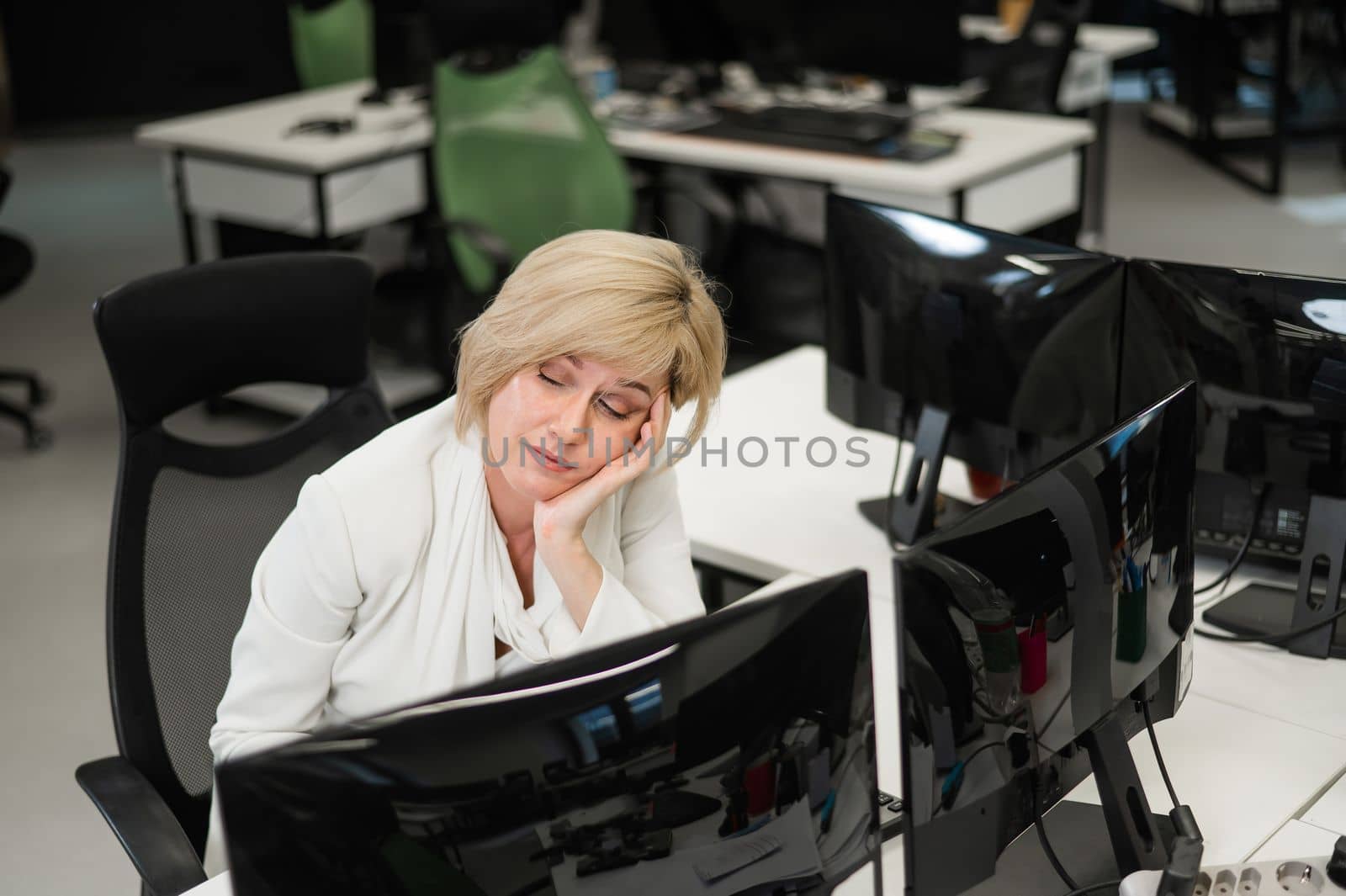 Caucasian blonde woman sleeping at her desk in the office