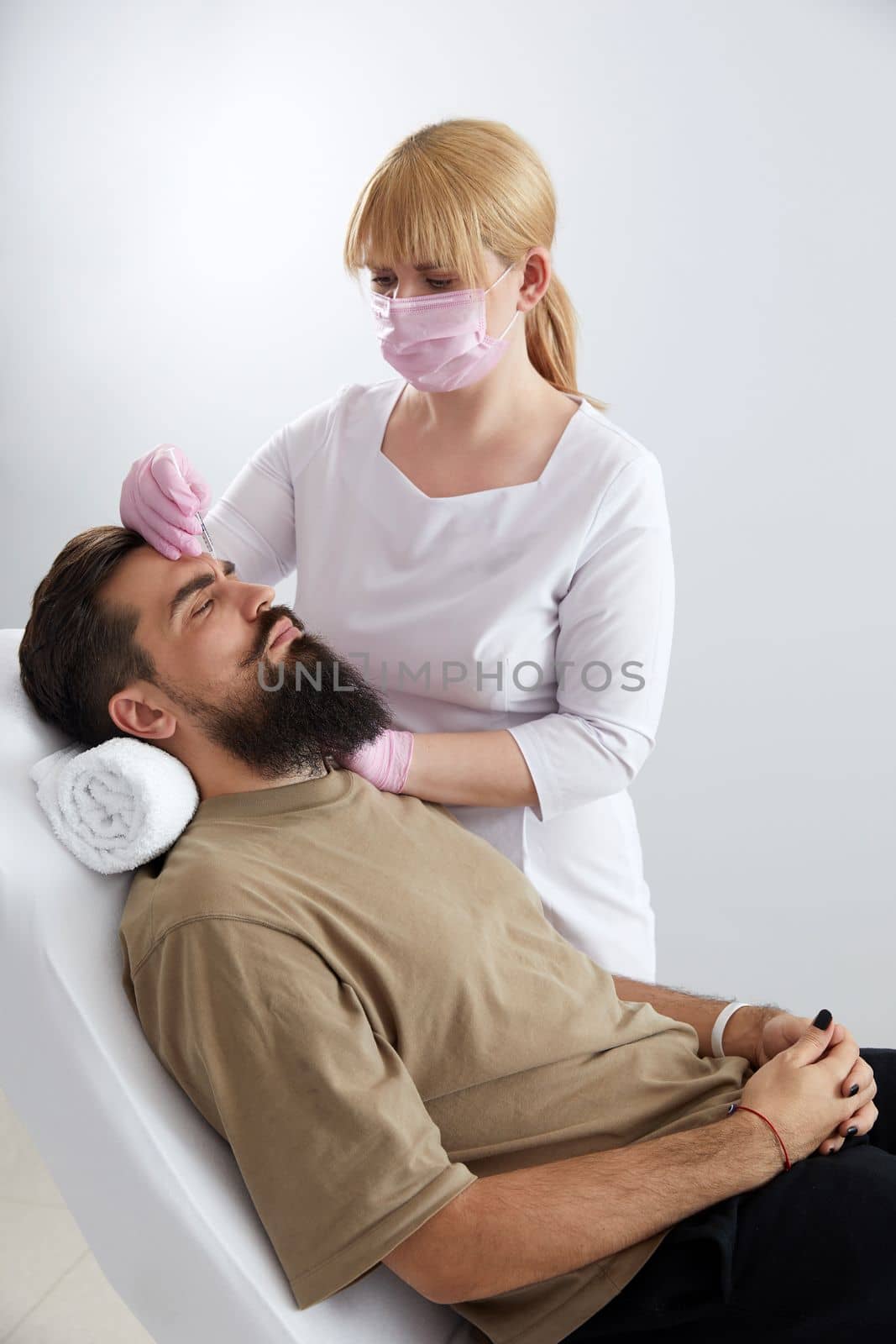 Closeup of bearded man getting beauty injection at aesthetic clinic. Plastic surgeon injecting anti-aging filler in handsome man face. Male cosmetology,