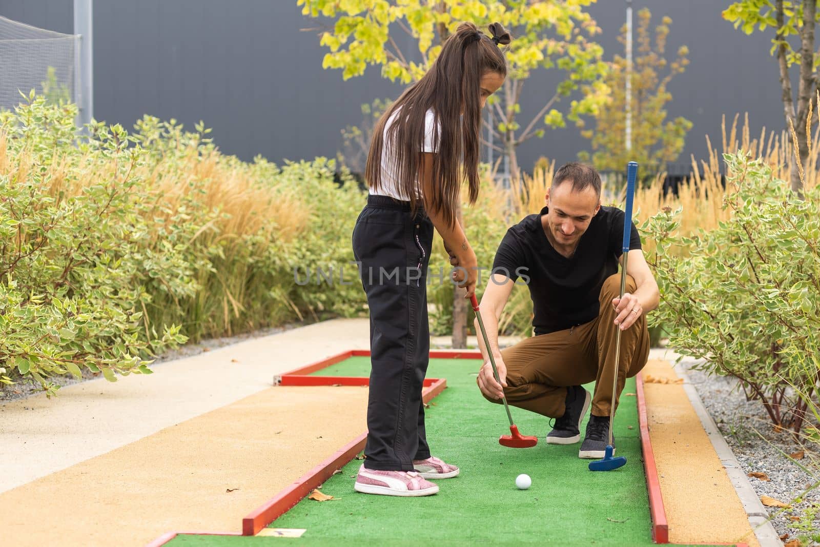 father and daughter playing mini golf together in the park by Andelov13