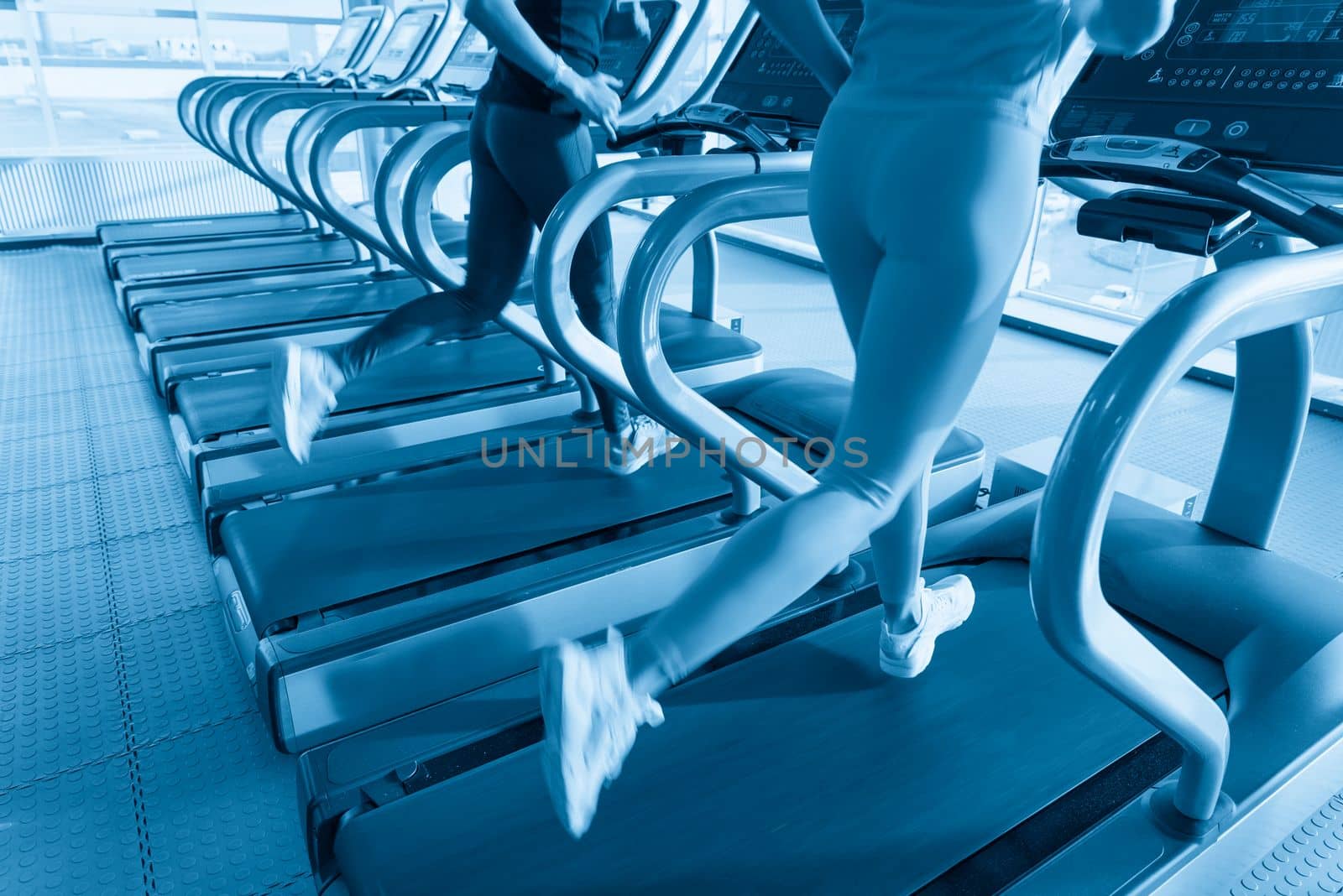 Two young women running on treadmill in a gym
