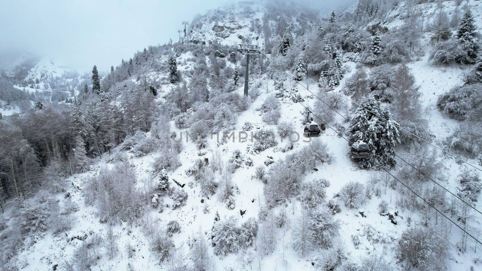 Cable car in the mountains in the winter forest by Passcal