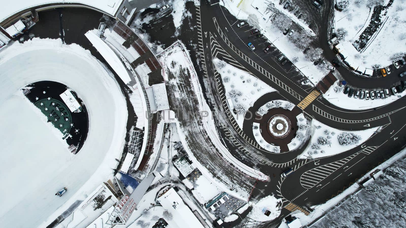 Winter alpine skating rink Medeo in the mountains. Drone view of the snowy forest and mountains. White clouds and fog in the gorge. Snow removal is underway. A large stadium. Almaty, Kazakhstan