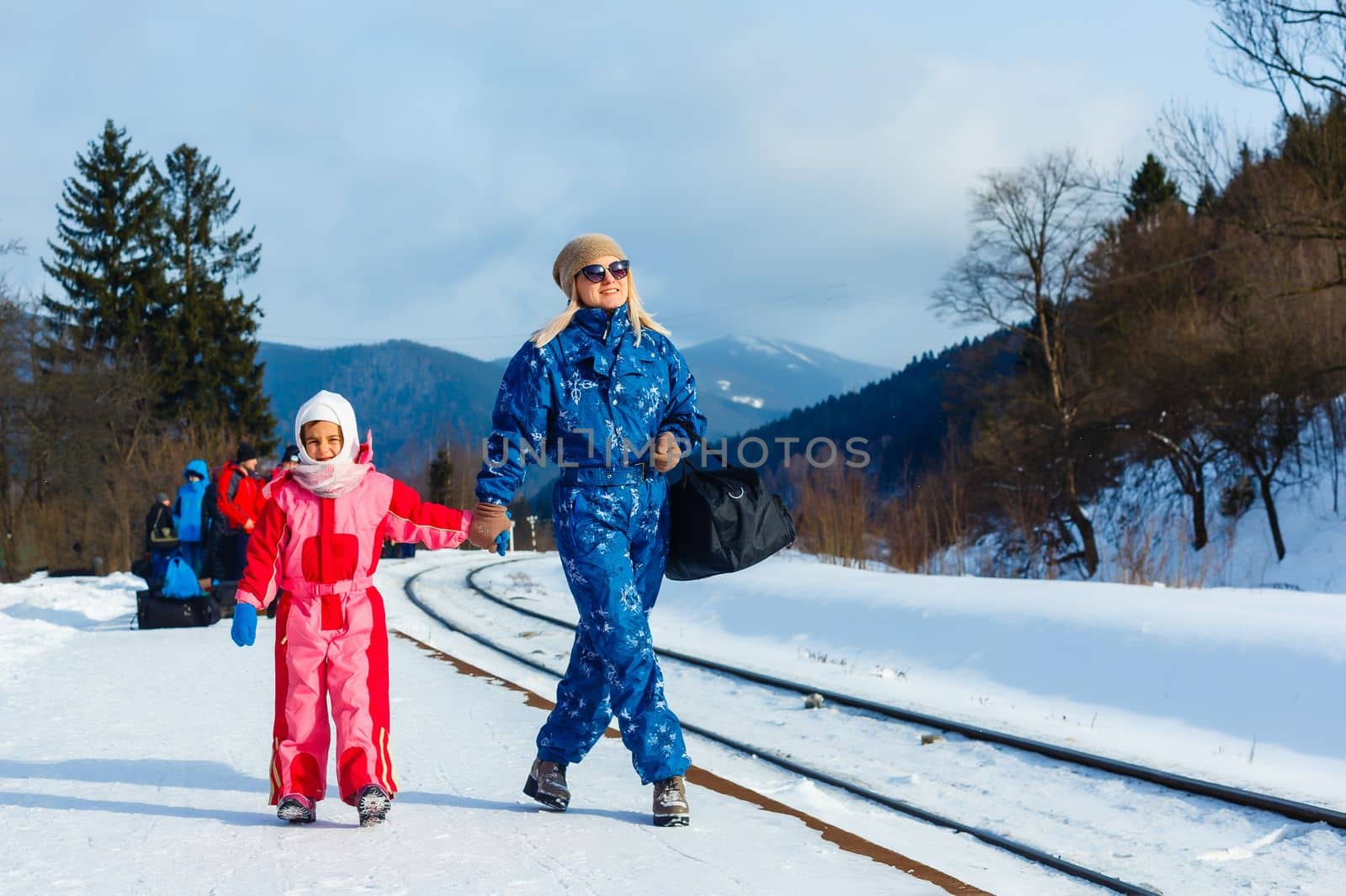 mother and daughter are wearing ski suits near the railway