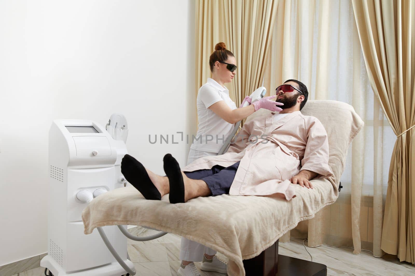 Bearded man getting laser facial treatment by professional cosmetologist in a beauty clinic. Healthy man lifestyle concept