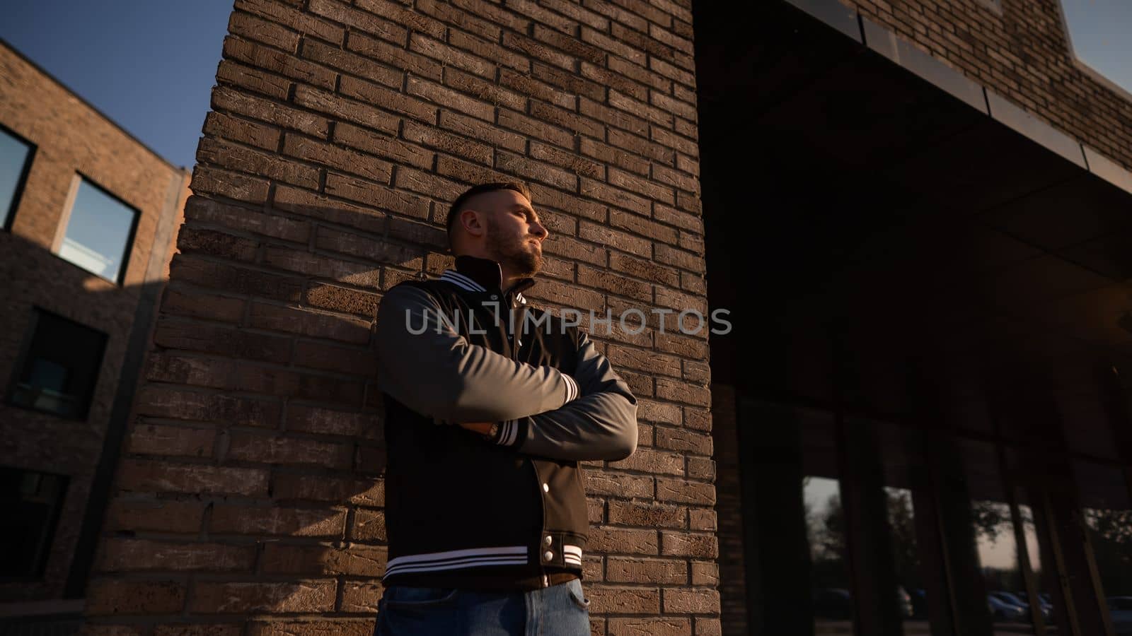 Caucasian bearded man in a bomber jacket leaned against a brick wall. by mrwed54