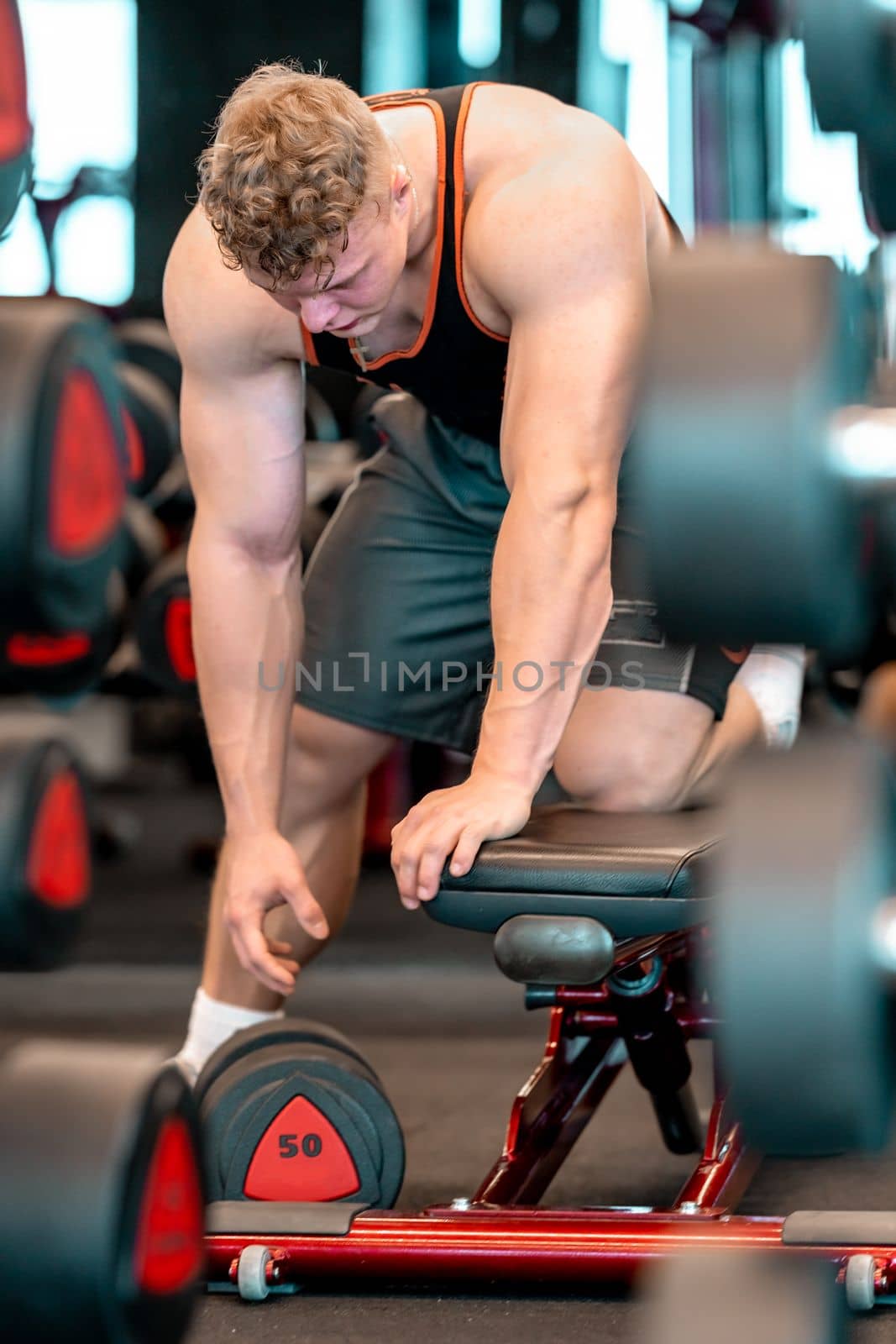 one-handed dumbbell pull-ups in a forward bend on a bench. High quality photo