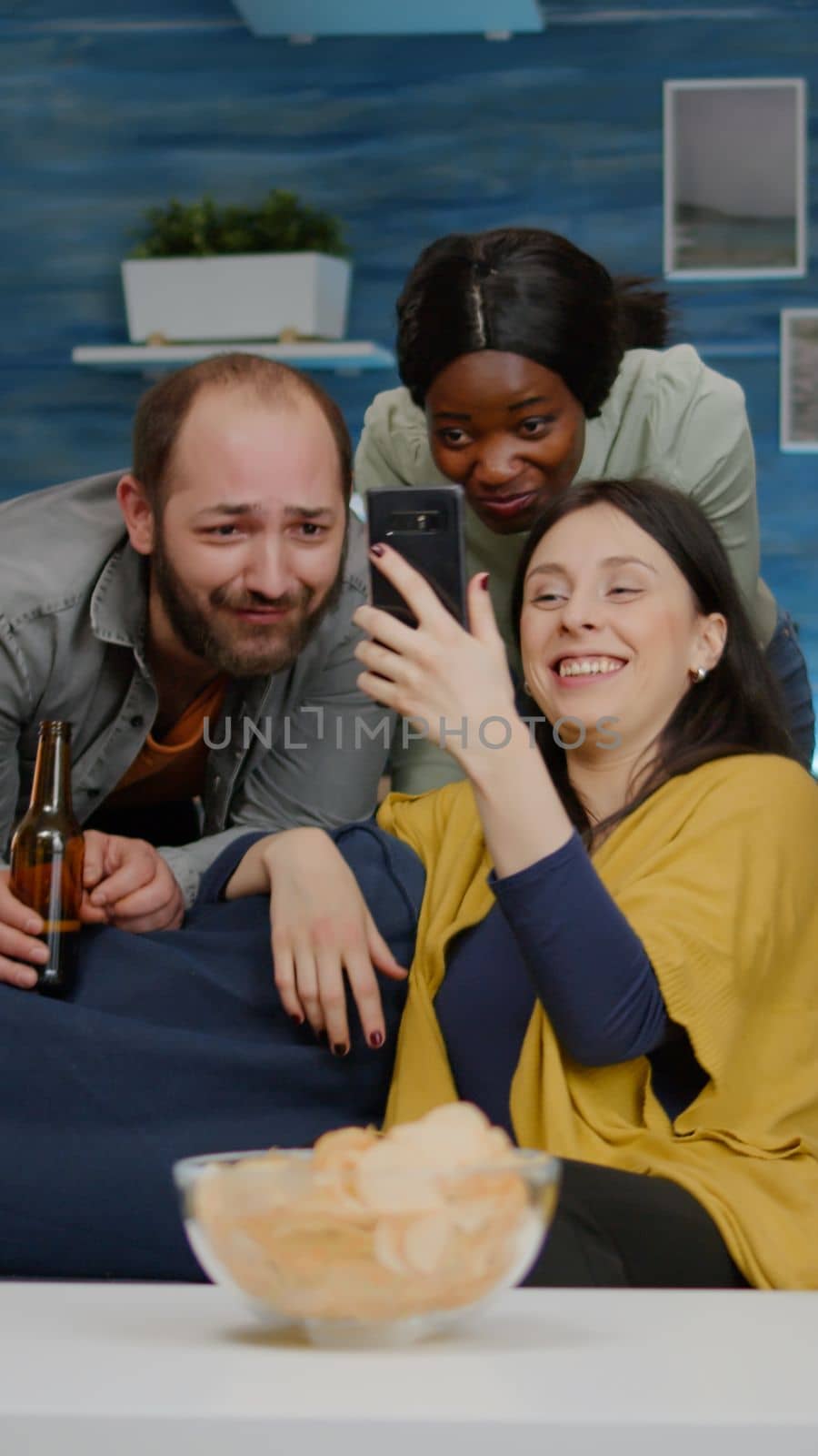 Mixed race friends chilling in living room during night party while watching online movie by DCStudio
