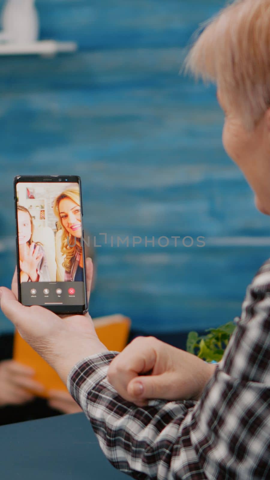 Senior woman having video call online talk with nephew using smartphone sitting in living room. Retired granny using modern internet online tech to connect with grandparents