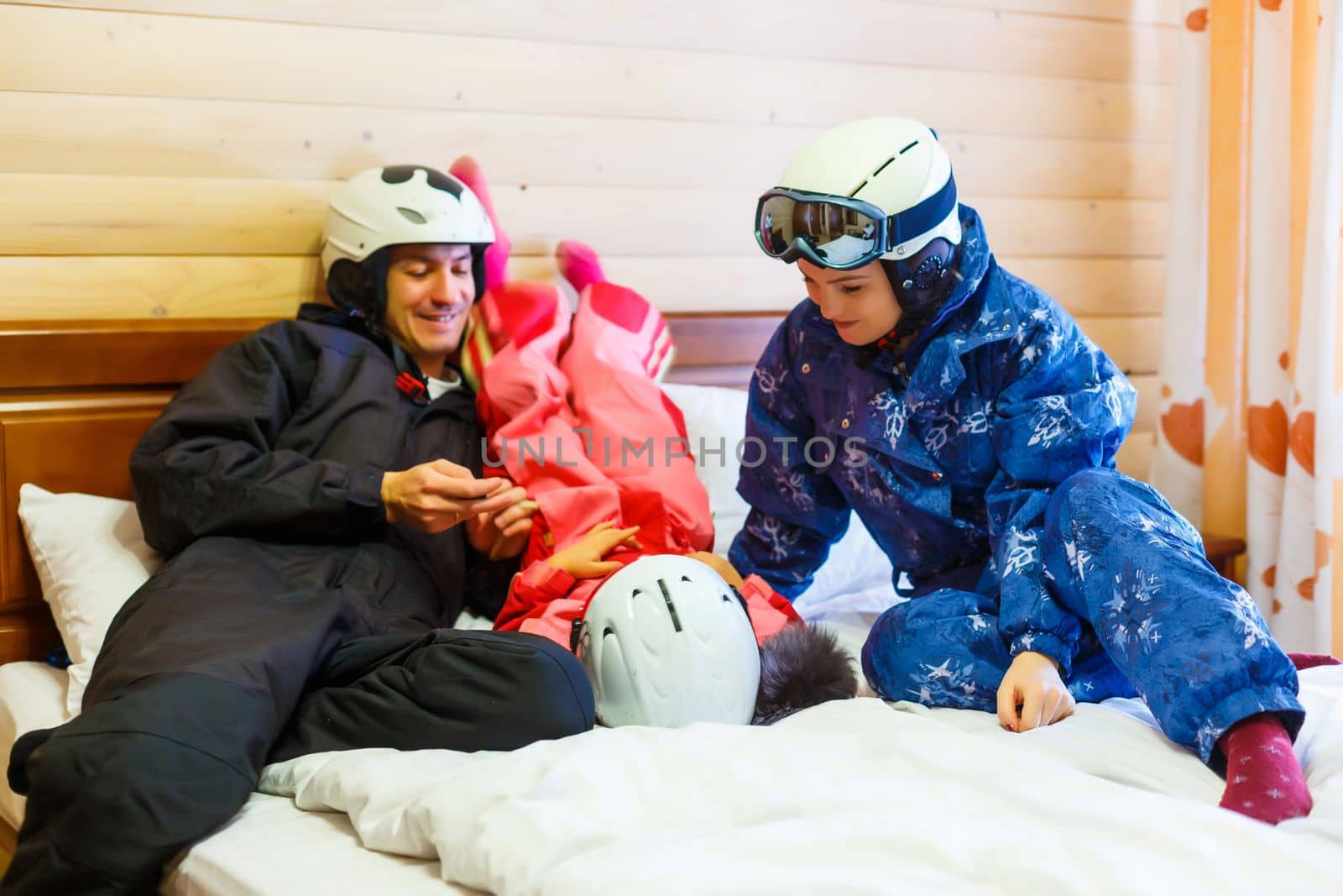 family resting on bed after skiing