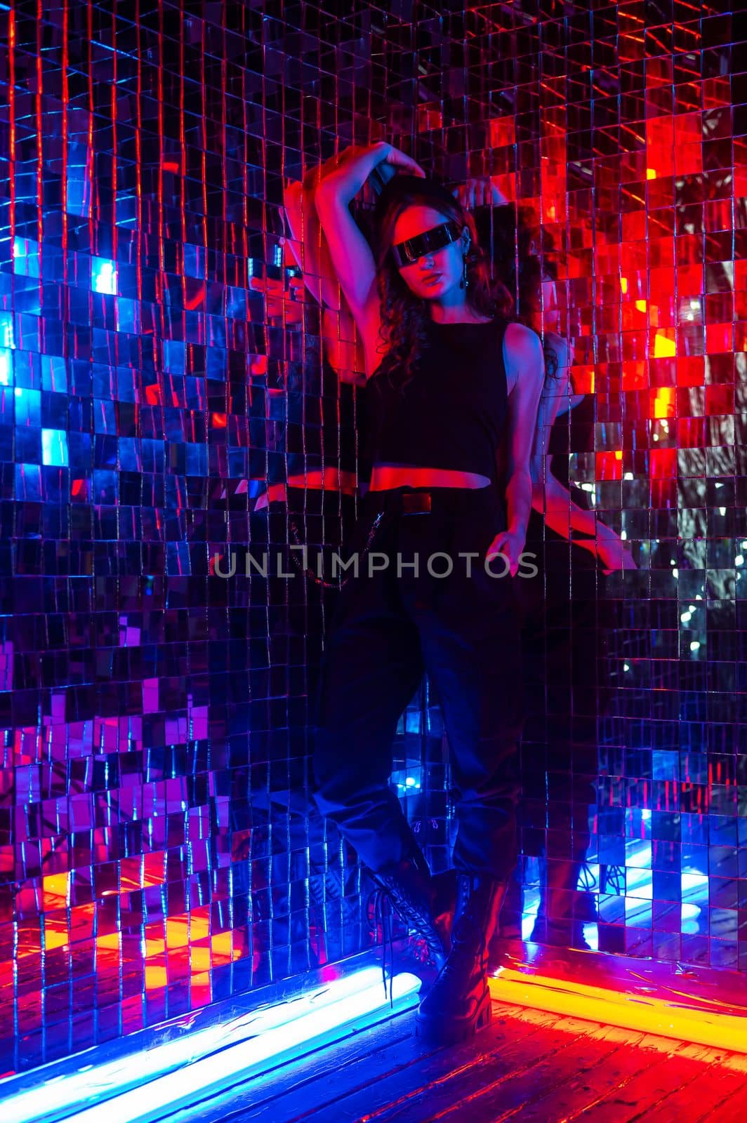 Portrait of a caucasian woman in sunglasses in neon light against a mirror wall. by mrwed54