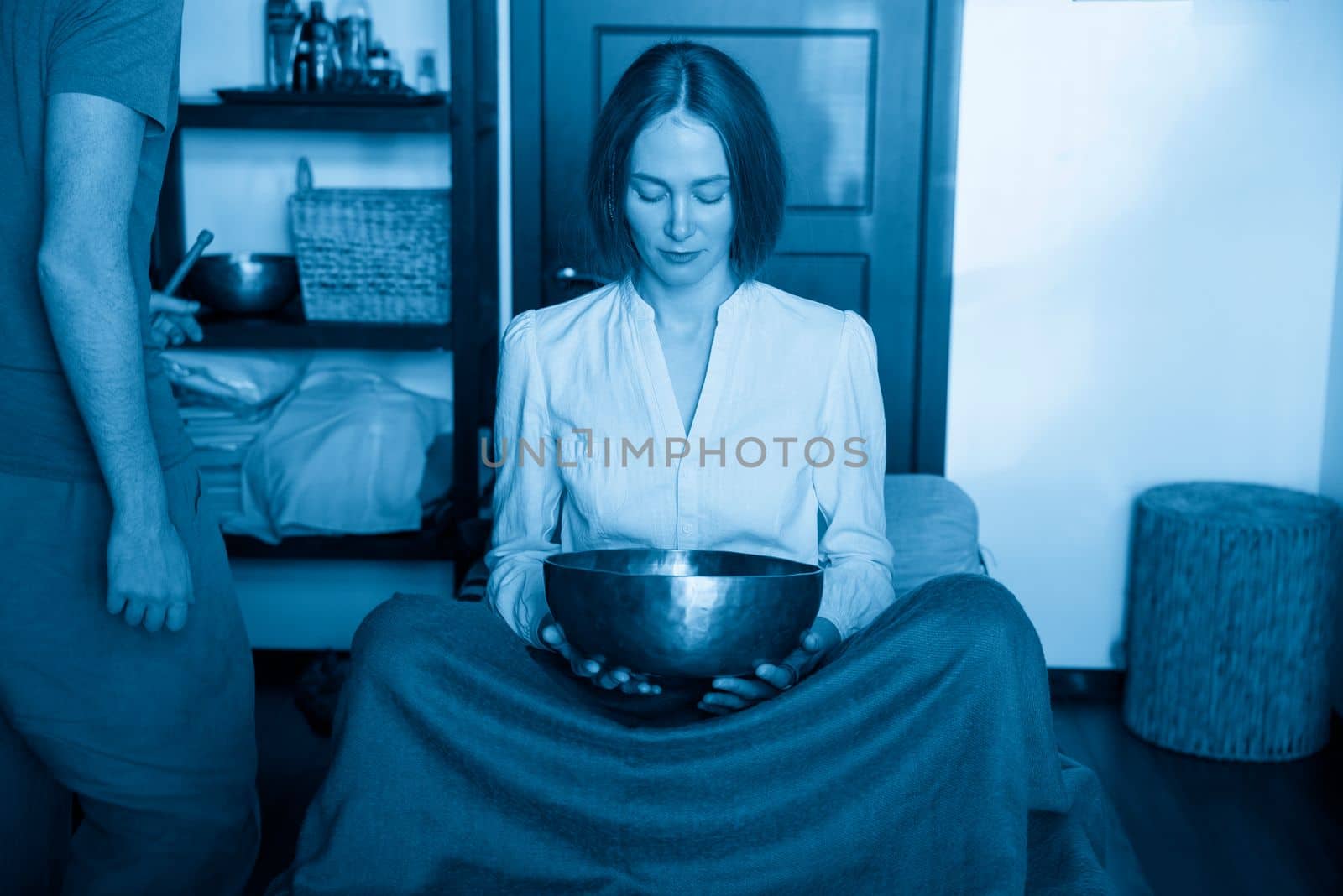 Woman holding Tibetan singing bowl in sound therapy in spa center by Mariakray