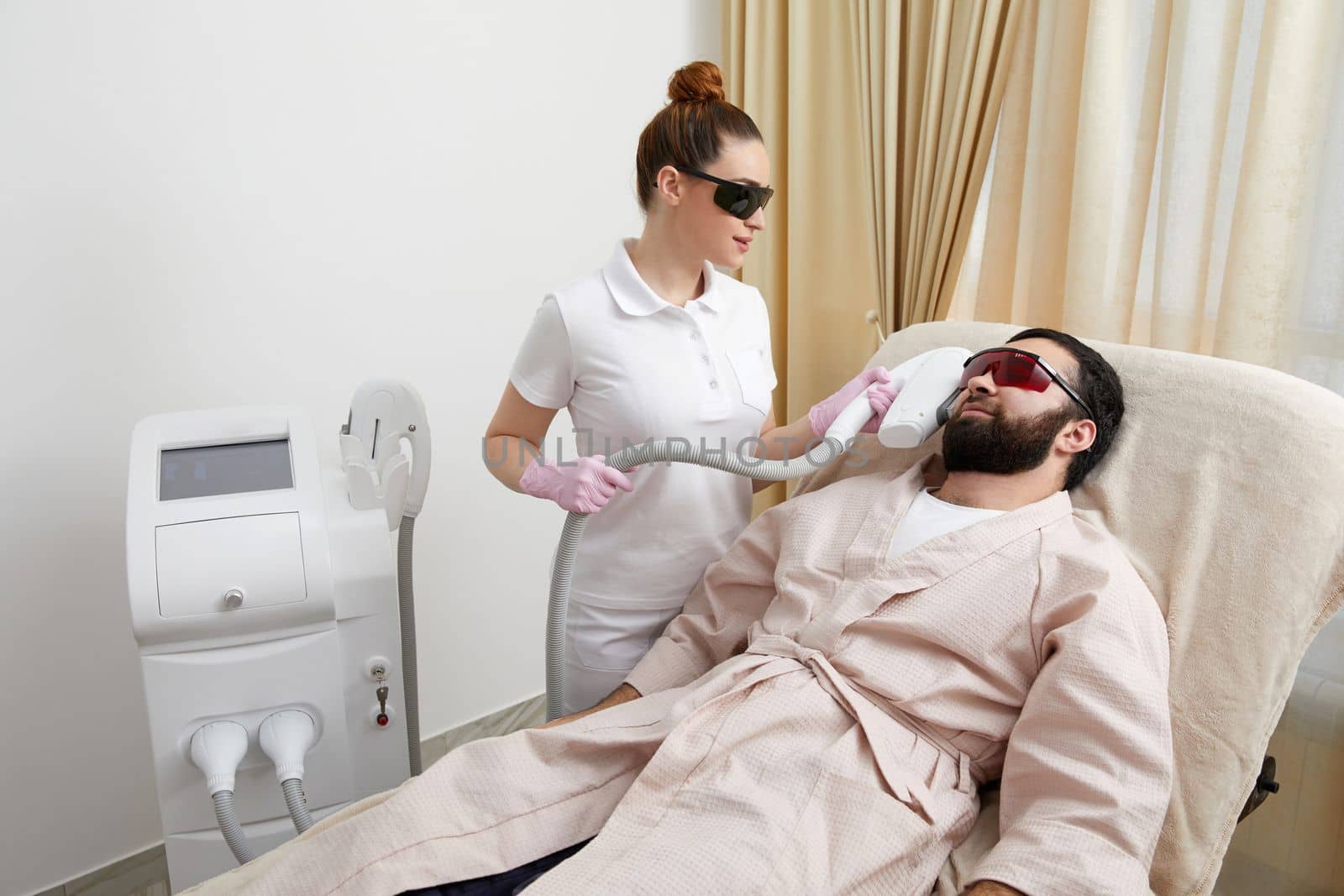 Bearded man getting laser facial treatment by professional cosmetologist in a beauty clinic. Healthy man lifestyle concept