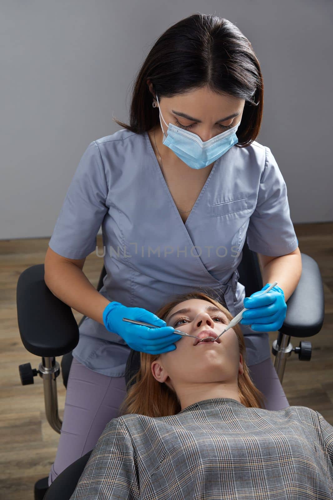 Dentist checking teeth of a female patient with dental mirror by Mariakray