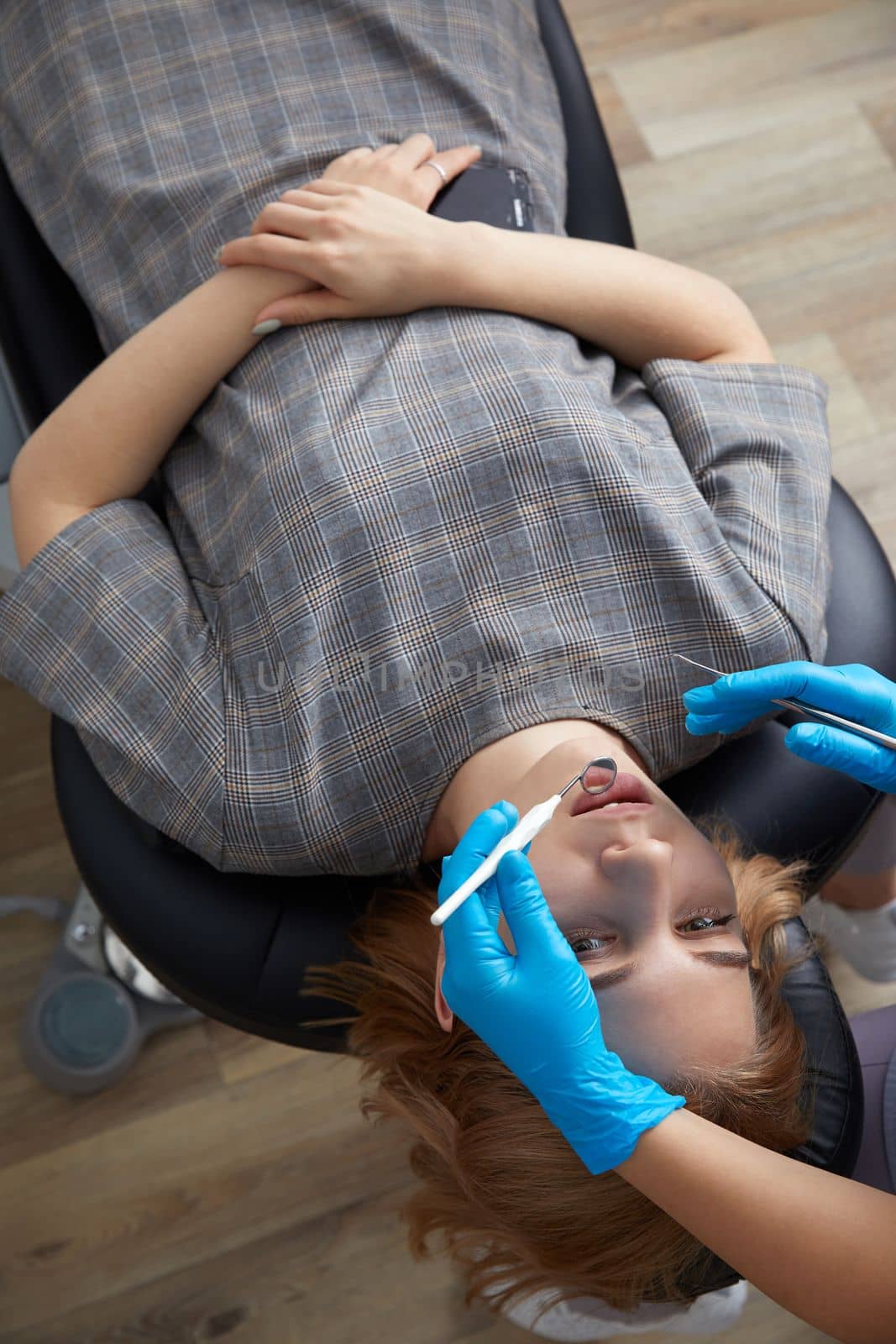 Dentist checking teeth of a female patient with dental mirror by Mariakray