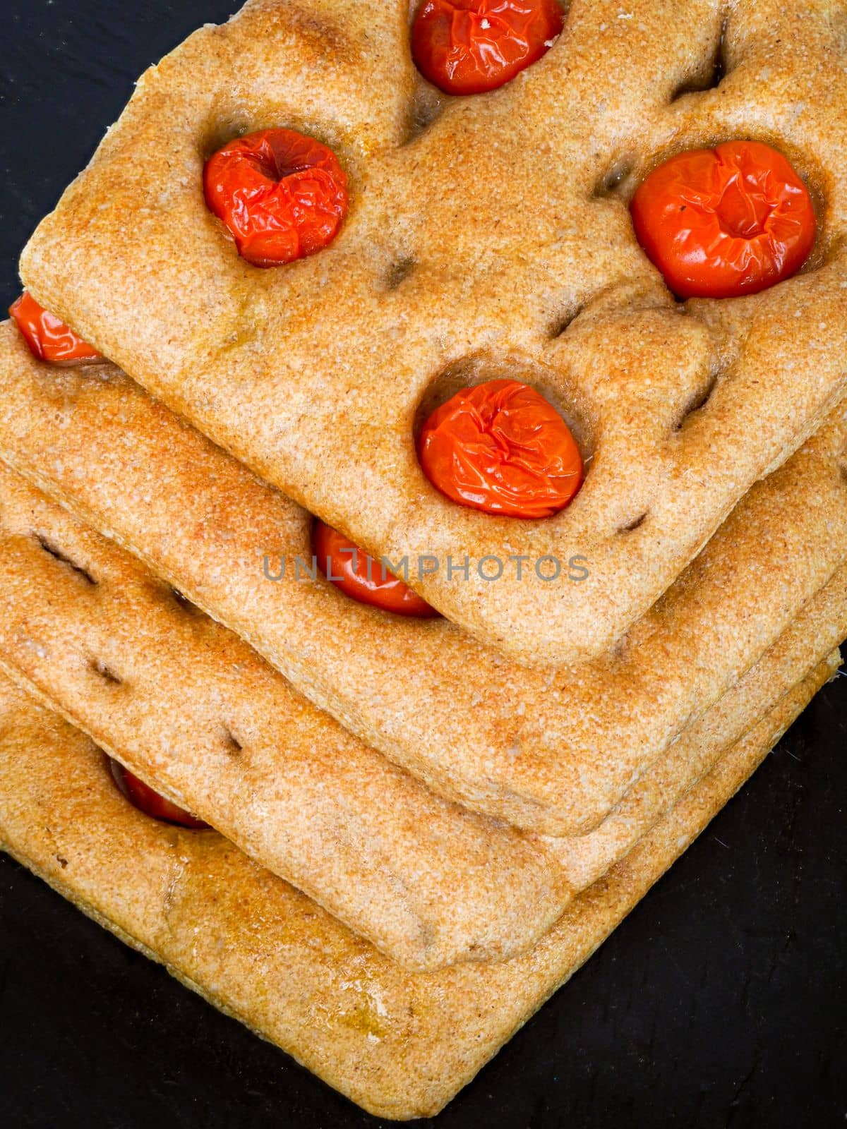 Italian flat bread organic wholewheat focaccia with tomatoes isolated in studio over a background