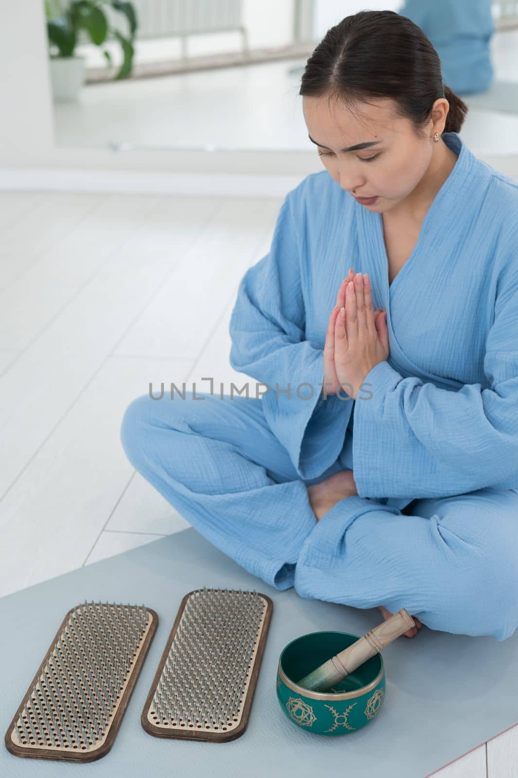 Asian woman sitting on yoga mat with tibetan singing bowl and sadhu boards. by mrwed54