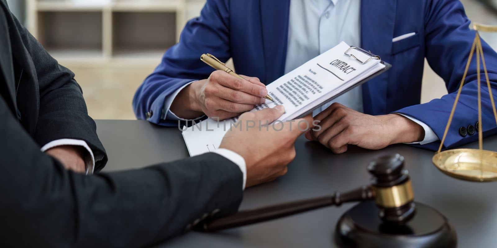 Business people and lawyers discussing contract papers with brass scale on wooden desk in office. Law, legal services, advice, Justice concept.