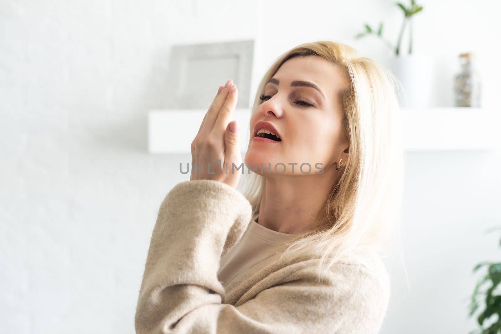young woman check her breath with the palm
