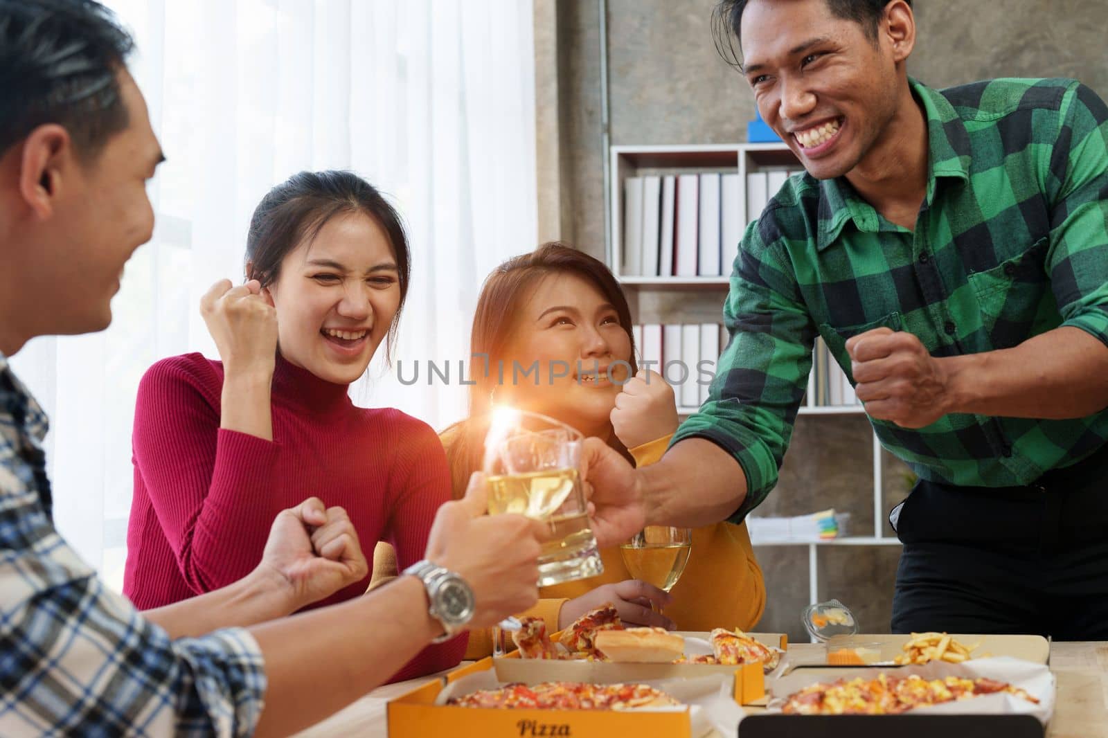 Friends at birthday party clinking glasses with champagne and pizza, enjoying Christmas vacation, pizza on the table. Holiday Party event