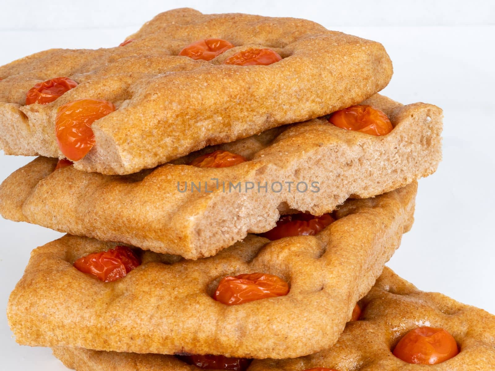 Italian flat bread organic wholewheat focaccia with tomatoes isolated in studio over a background