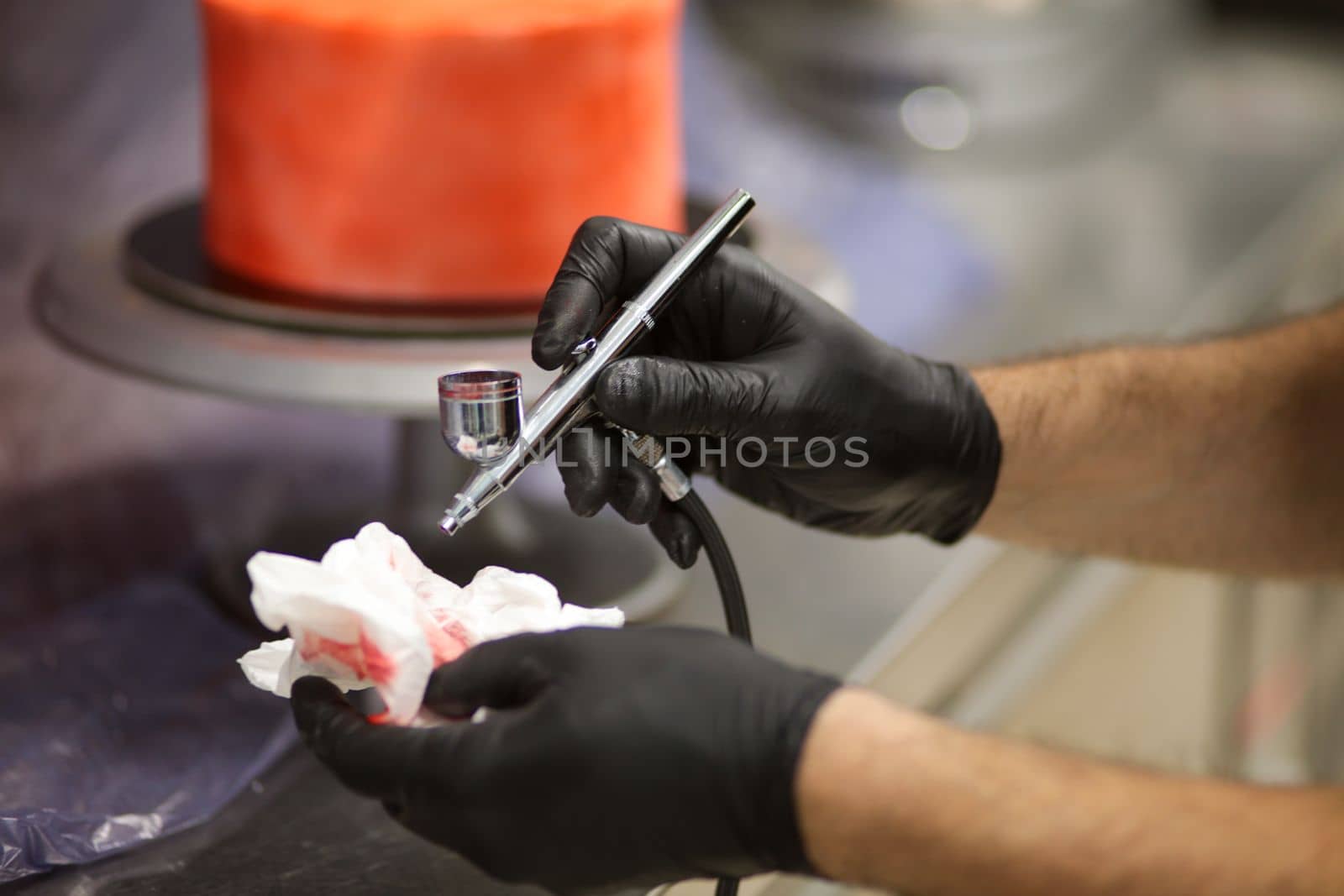 cook preparing a red frosted cake using air bush