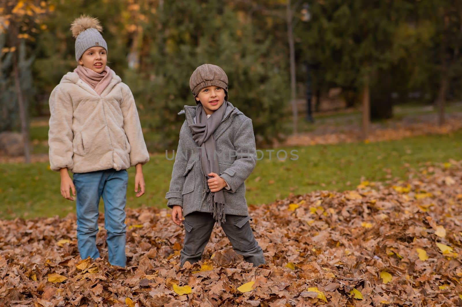 Caucasian children walk in the autumn park. Brother and sister in coats