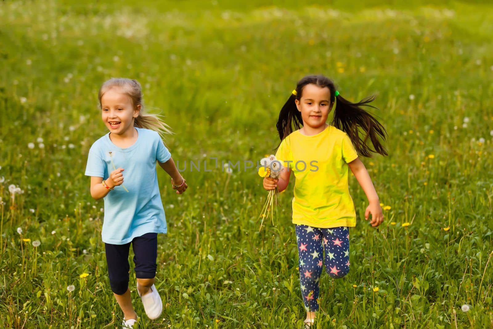 Little pretty girls having fun outdoor. Two cute girls are running on green grass. Best friends by Andelov13