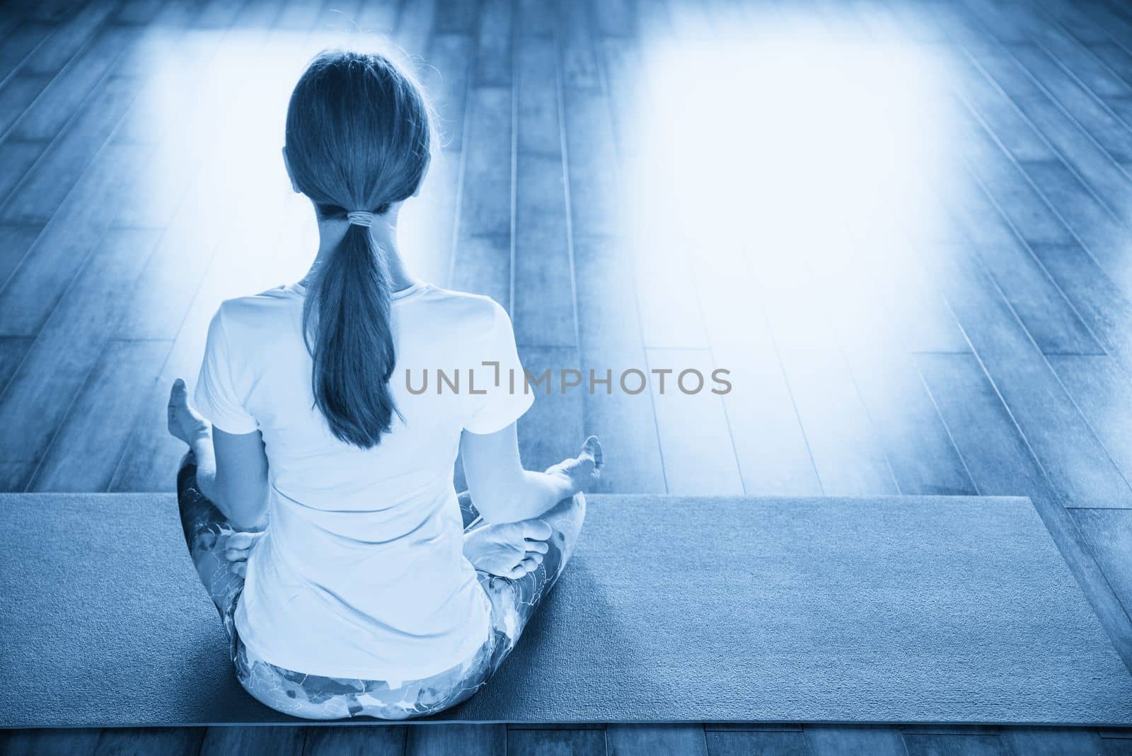 Young woman meditating sitting in lotus position by Mariakray