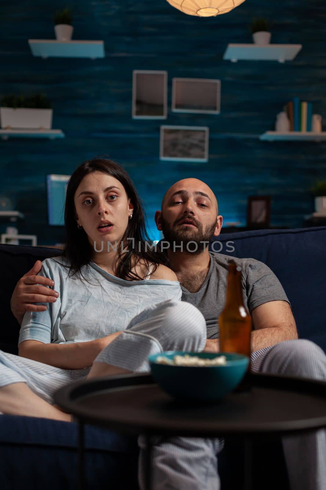 POV of couple watching broadcast show on TV channel, enjoying leisure activity with film on television. Man and woman using electronic program to watch movie, drinking beer and eating popcorn.