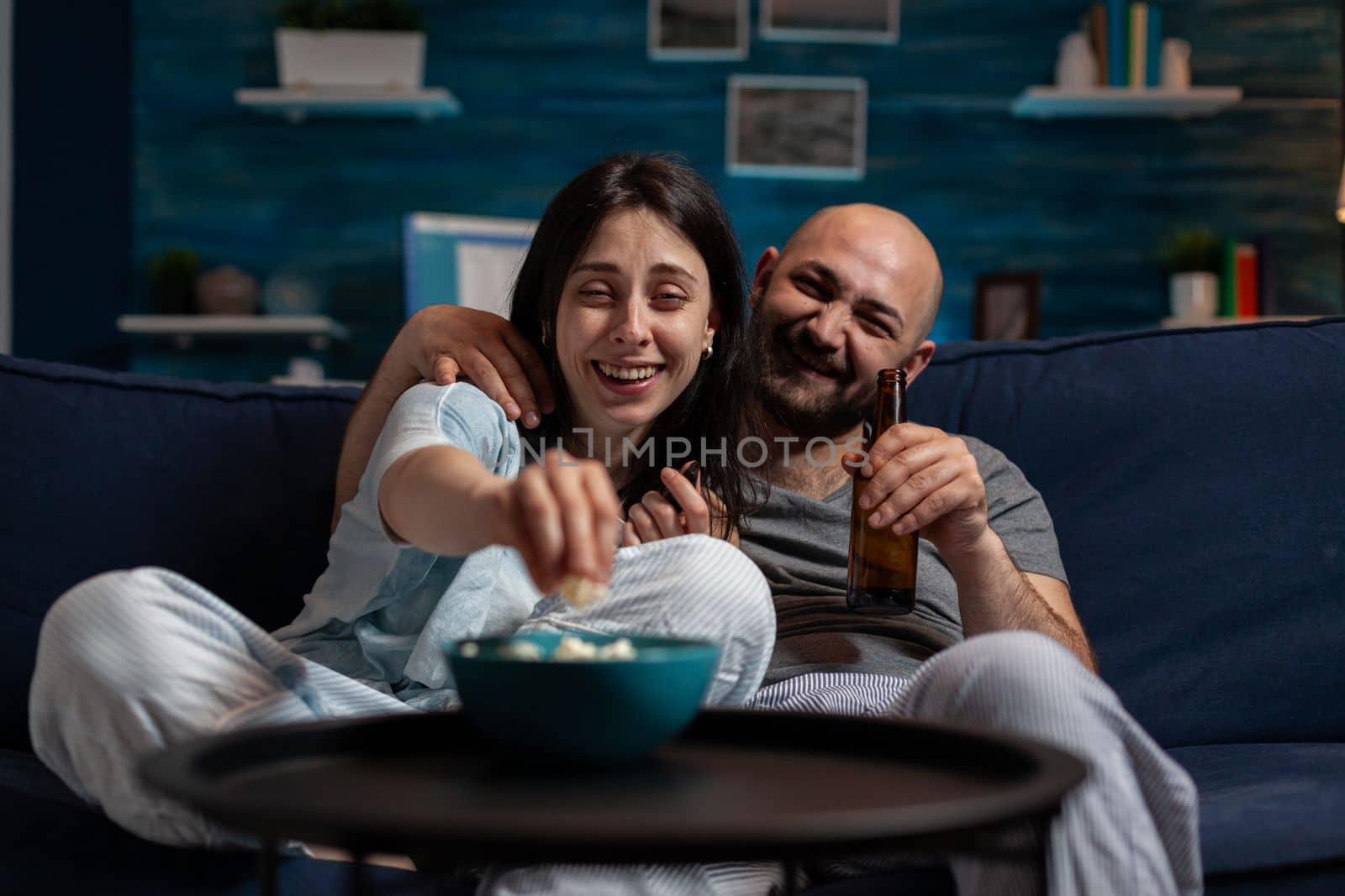 POV of happy partners having fun with movie on television program, doing leisure activity. Joyful girlfriend and boyfriend watching film on TV channel for entertainment and excitement.