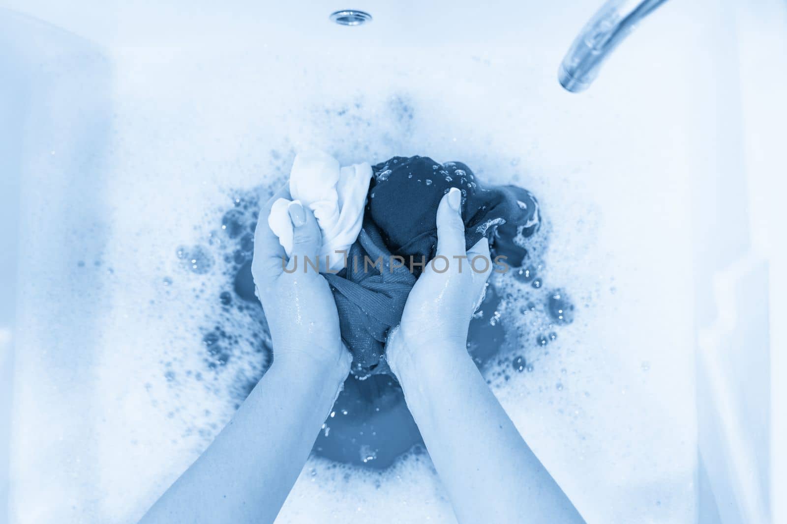 Female hands washing color clothes in basin