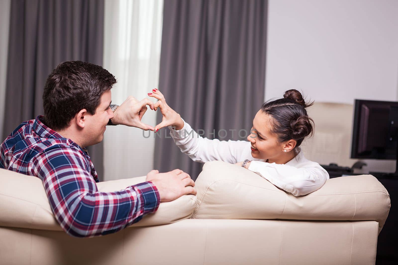 Man and woman making a heart symbol from their fingers. Love and romance