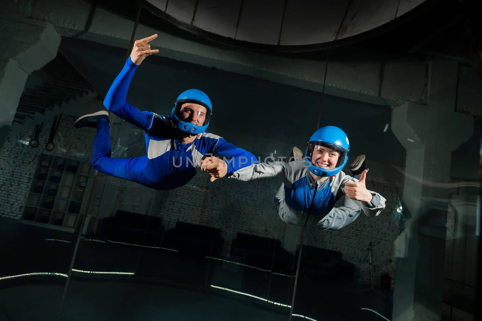 A man teaches a woman how to fly in a wind tunnel. Free fall simulator