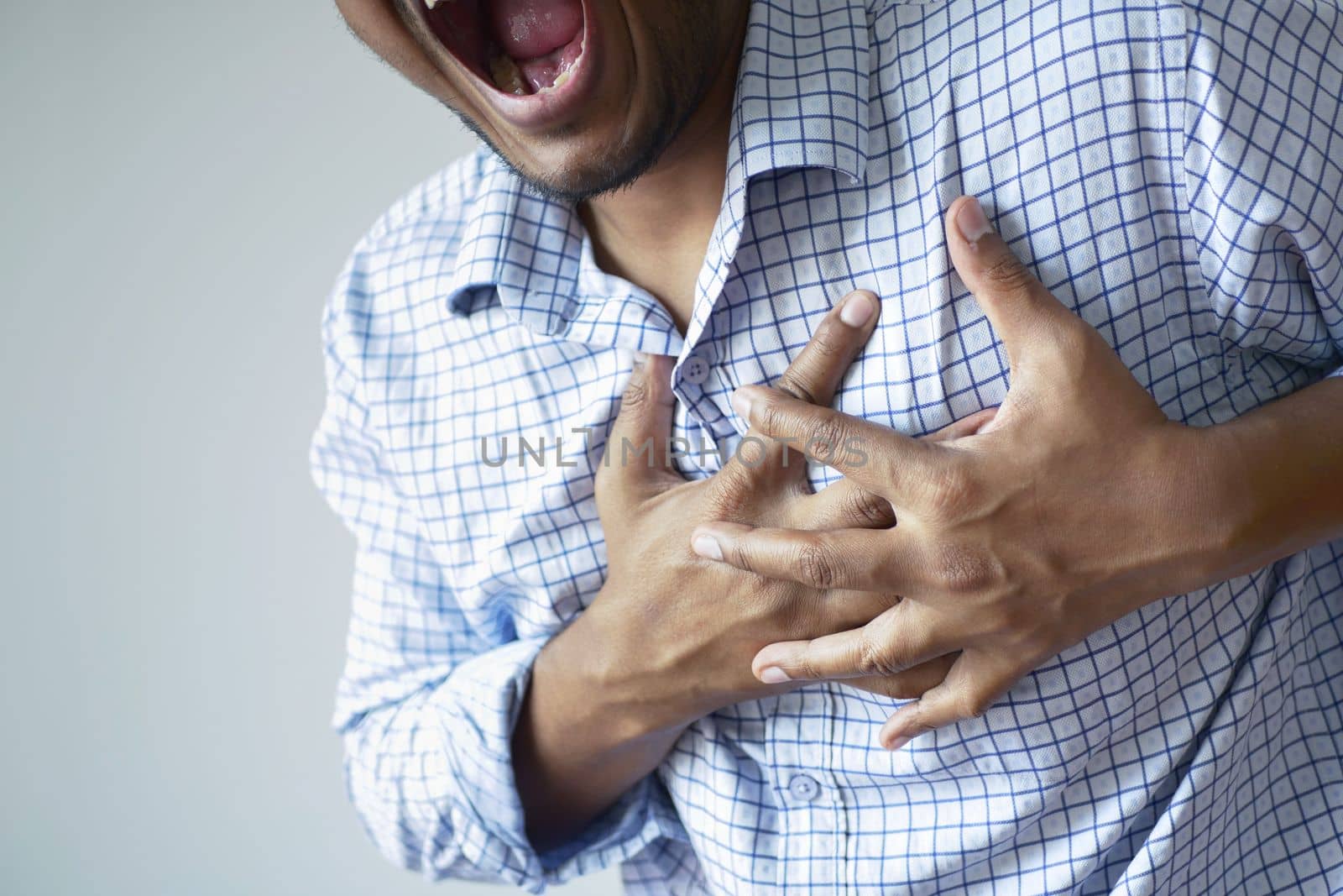 young man suffering pain in heart and holding chest with hand .