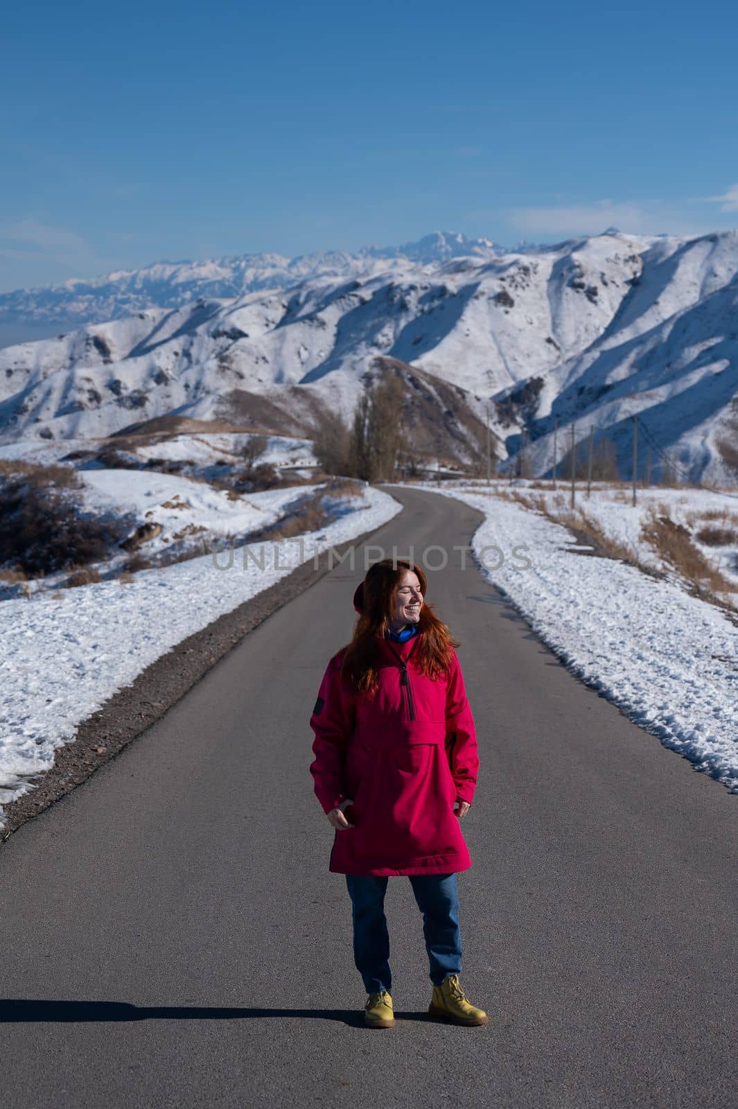 Red-haired caucasian woman in fuchsia-colored jackets in snowy mountains