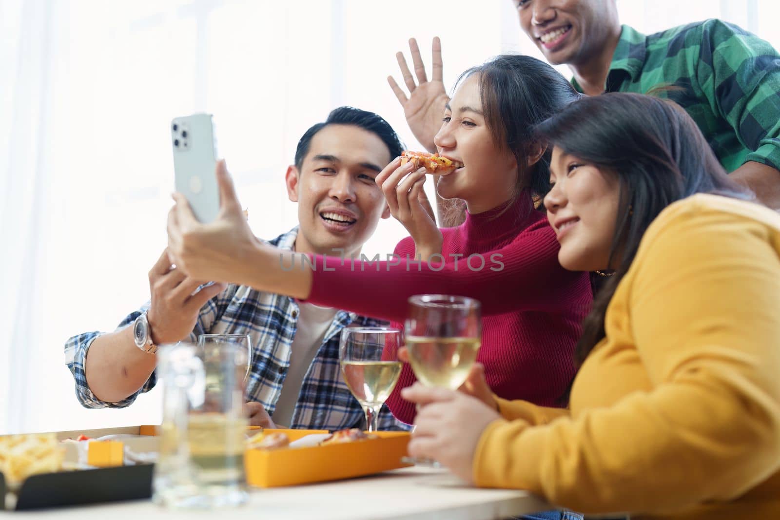 Friends at birthday party clinking glasses with champagne and pizza, enjoying Christmas vacation, pizza on the table. Holiday Party event