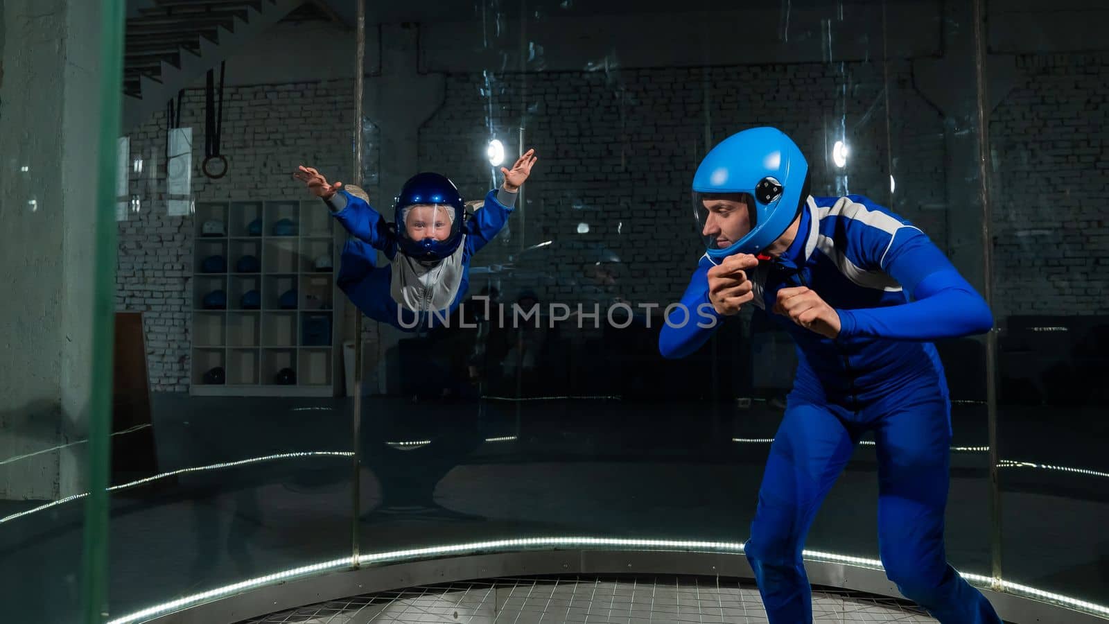 A man teaches a boy to fly in a wind tunnel. Lack of gravity