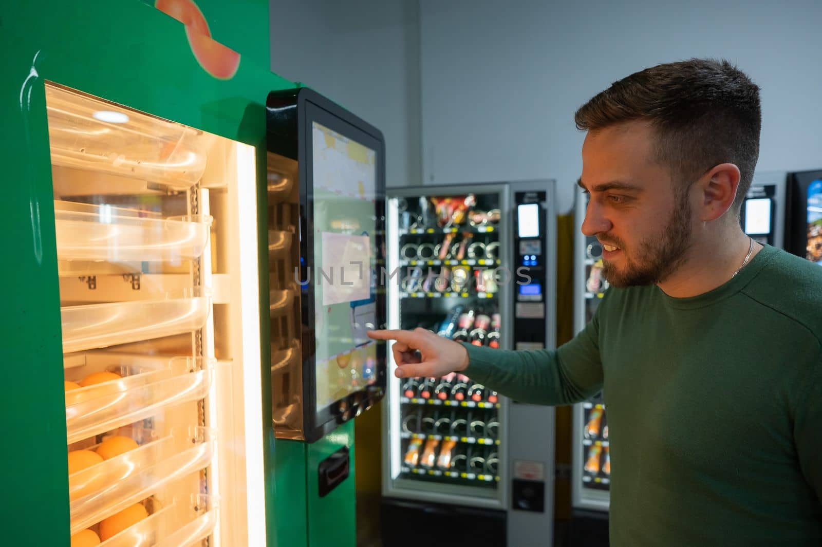 Caucasian man buys freshly squeezed orange juice from vending machine