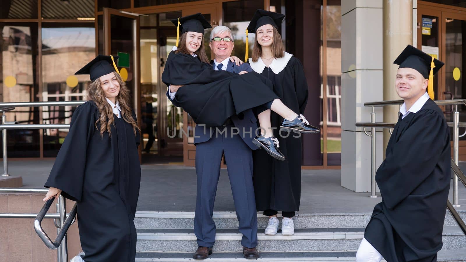 The teacher holds the graduate in his arms