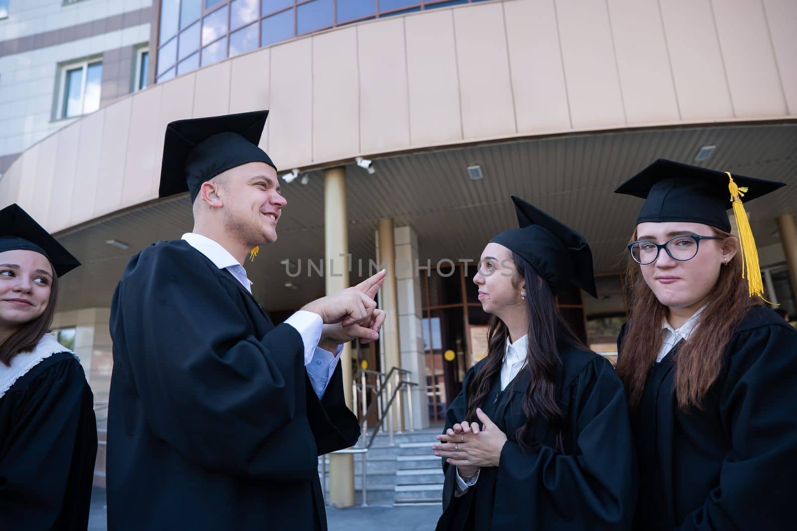 Happy students in graduate gown communicate in sign language. by mrwed54
