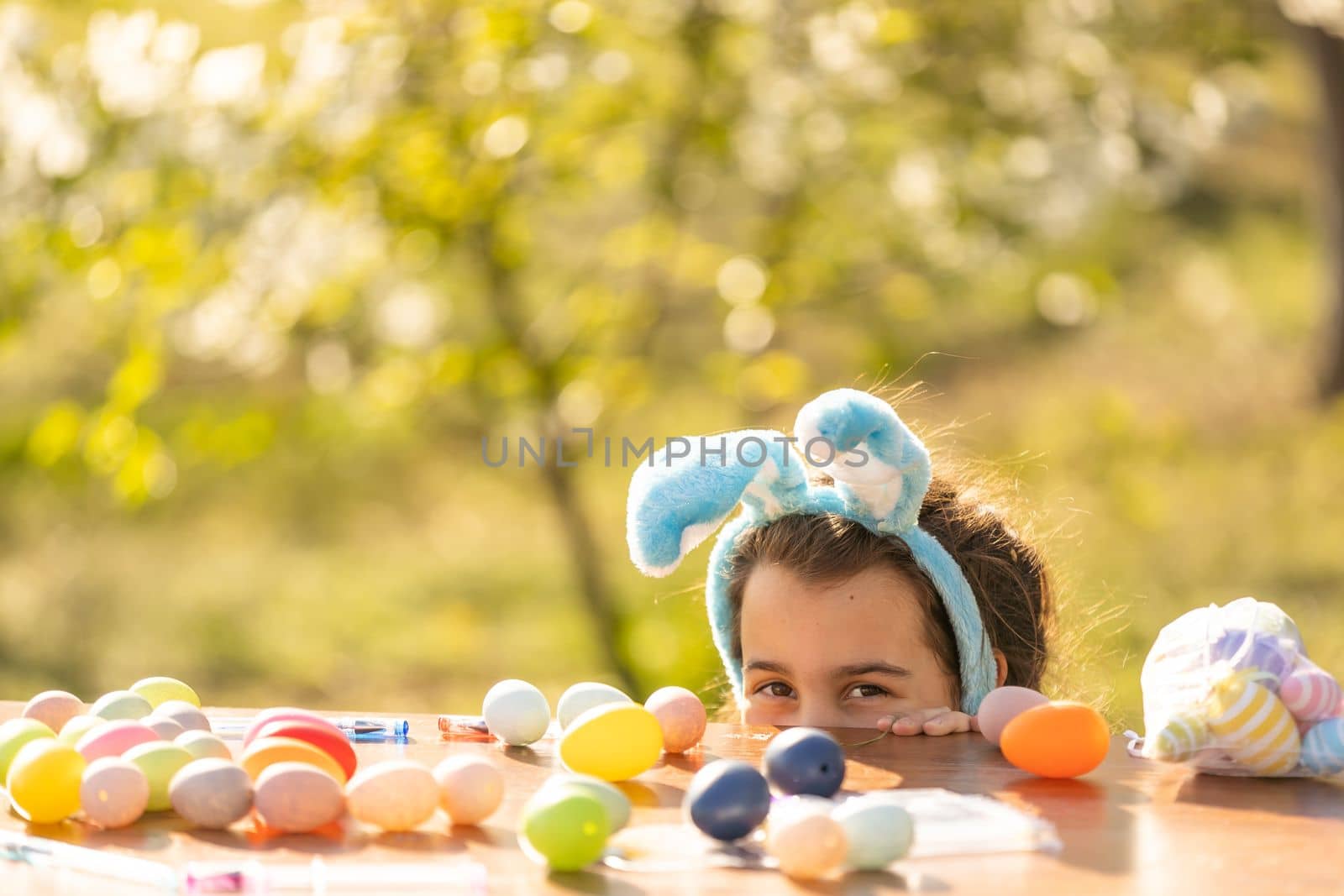 happy teen girl wear bunny ears with Easter eggs in the garden.