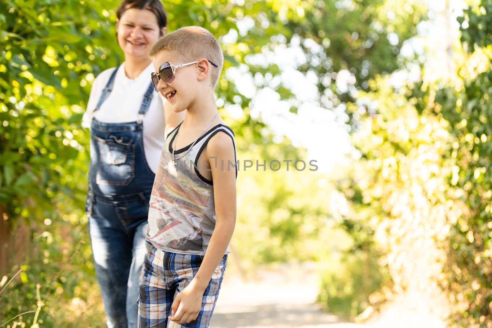 Pregnant woman walking countryside with her son. Child hugging his pregnant mother. by Andelov13