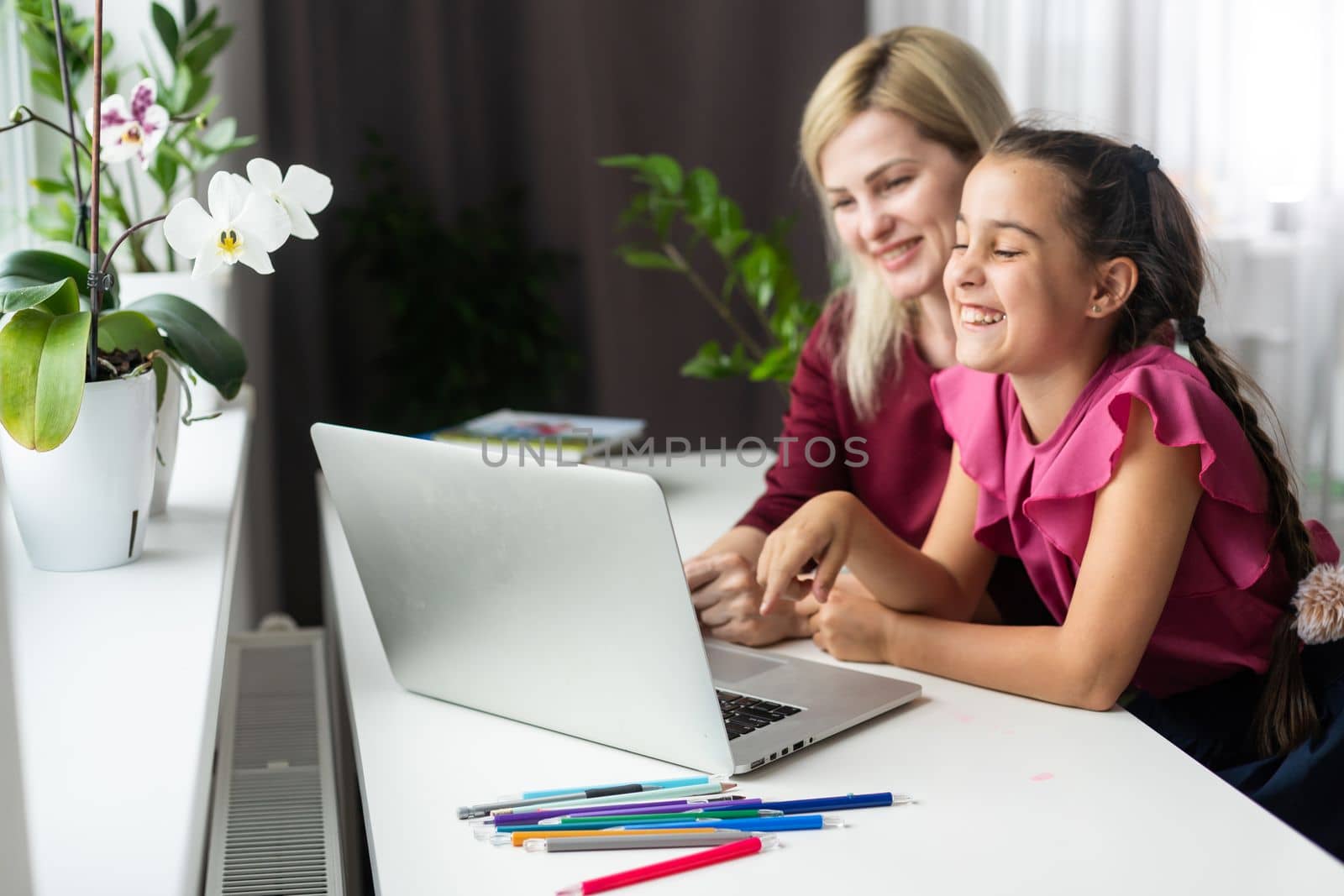 Beautiful young mother helping her younger daughter with homework.