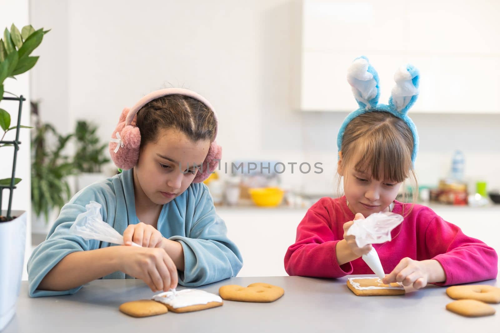Portrait of happy small children decorating homemade cookies in kitchen and making xmas cookies together at home by Andelov13