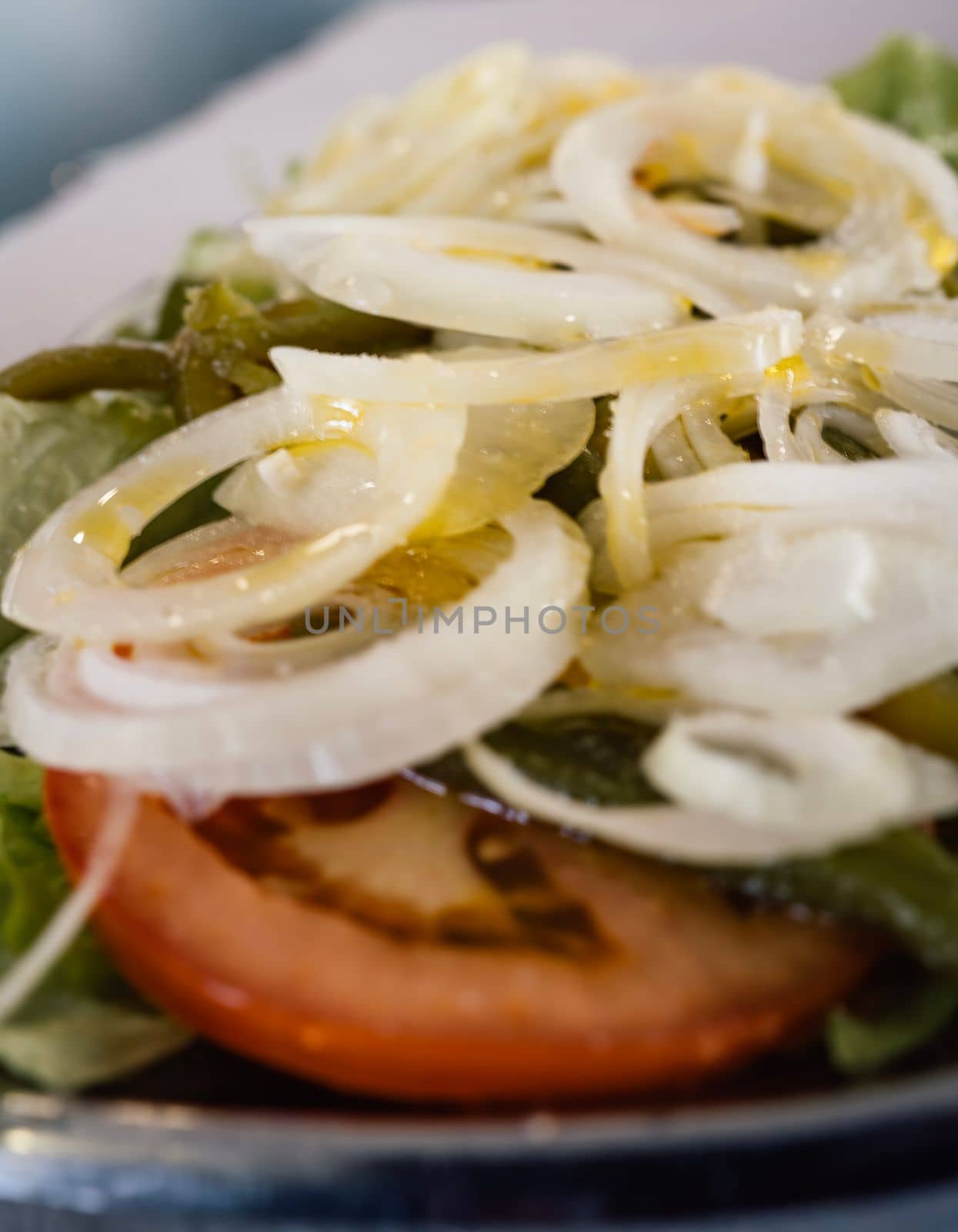 Close up of fresh salad with lettuce , onion , tomato and oil.