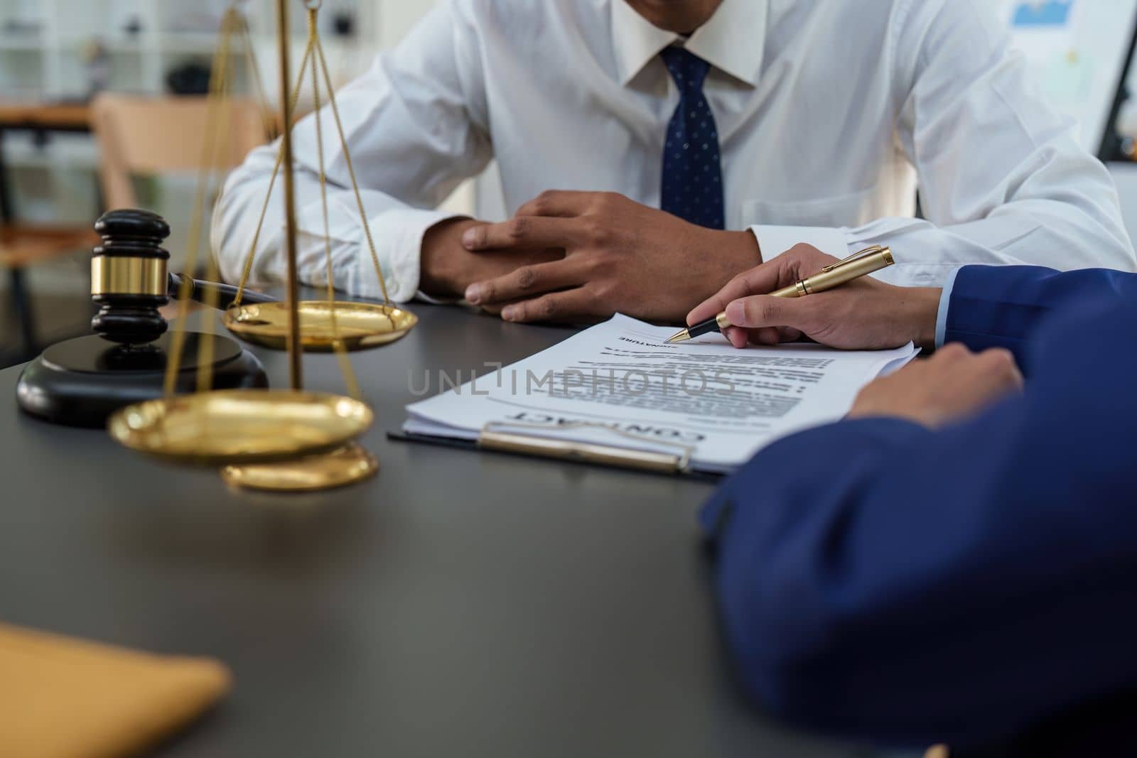 Business people and lawyers discussing contract papers with brass scale on wooden desk in office. Law, legal services, advice, Justice concept by itchaznong