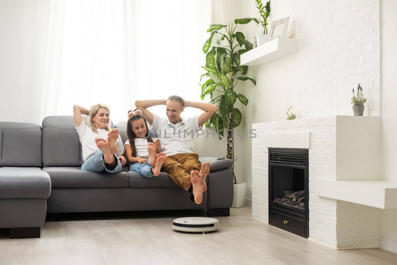 Smiling family pointing at robotic vacuum cleaner.