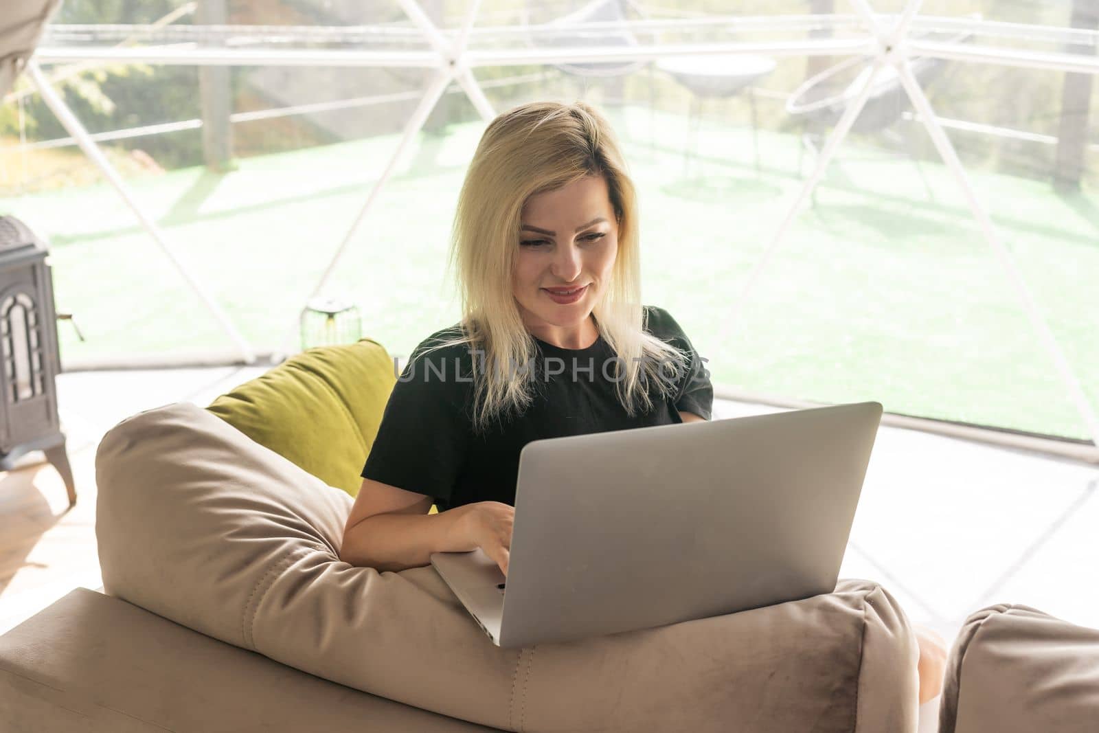 Happy young woman chatting online by using laptop in dome camping. Glamping vacation concept by Andelov13
