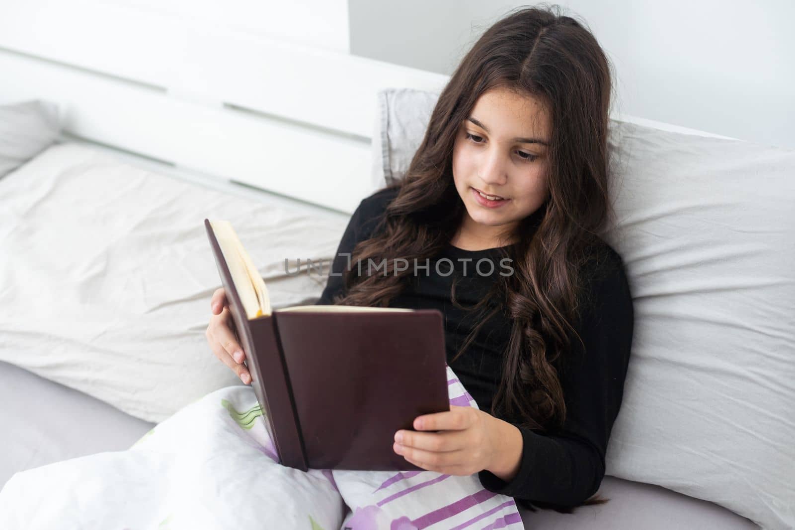 teenage girl with a book in bed by Andelov13